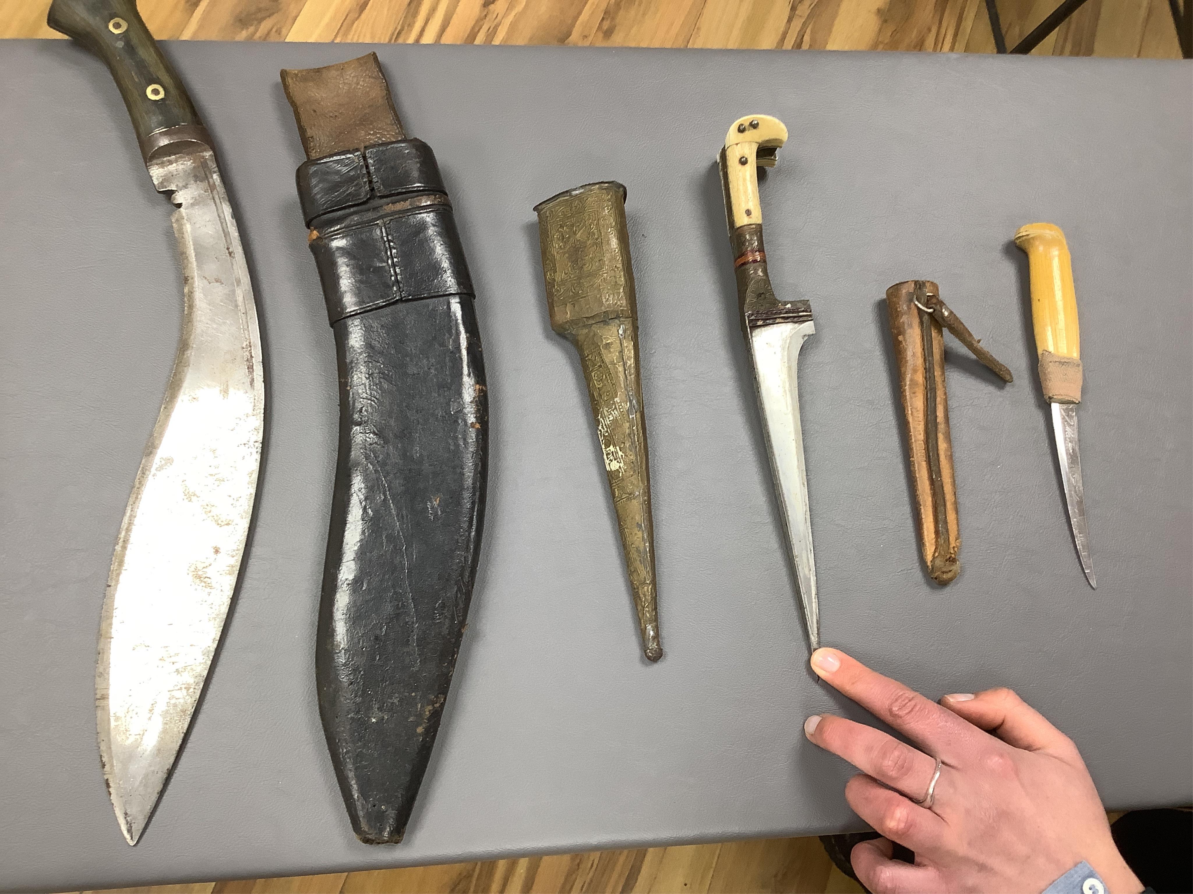 Eighteen assorted world weapons comprising a silver jambya (pommel missing), a knobkerry, a dha, two kris (one with handle missing), a lohar, three kukris, a djambok, a Chinese trousse, a chora, a flyssa, five others and